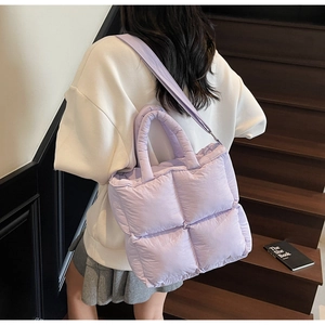 Detail view of purple quilted puffer tote bag with handles and crossbody strap