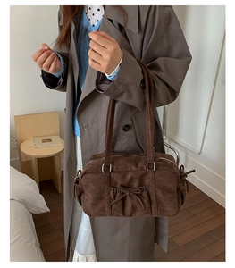 Détail d'un sac à main en daim marron foncé avec texture froncée et nœud décoratif