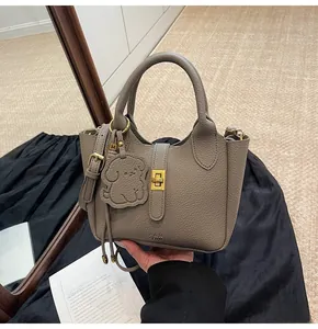 Detailed close-up of lychee textured handbag with gold lock and bear charm