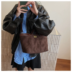 Détail du sac sous le bras en daim marron avec motif matelassé et fermoir doré chic