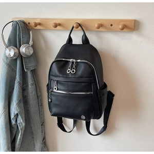 Detail of black lychee grain backpack featuring double silver ring zipper pockets