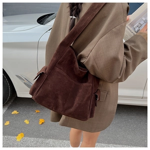 Détail du sac fourre-tout en daim marron foncé avec poches latérales et large bandoulière