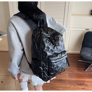 Detail of black padded backpack featuring delicate bow quilting and spacious compartments