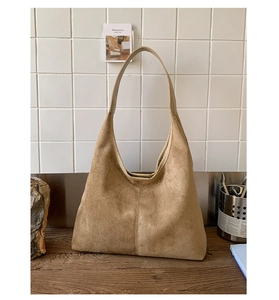 Close-up of caramel suede tote bag with matte texture on a minimalist wooden table