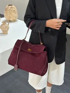 Detail showing the burgundy suede texture and gold square twist lock of this shoulder bag