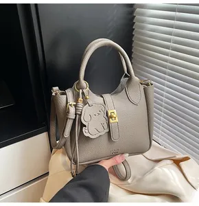 Detail of lychee pattern leather bucket bag in elephant grey with gold twist-lock and charm