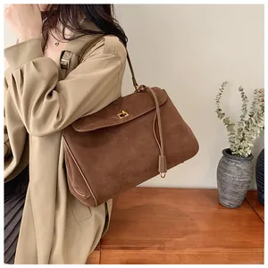 Detail of vintage brown suede shoulder bag featuring a gold twist lock and leather tassel