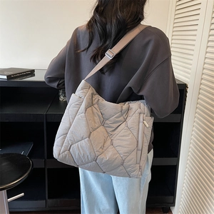 Quilted light gray puffer tote bag with wide adjustable shoulder strap and side zipper