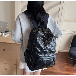 Detail of black quilted nylon backpack featuring embossed bear patterns and large pockets