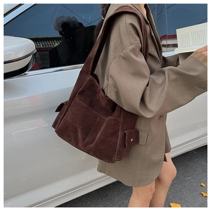 Détail du sac fourre-tout en daim marron foncé avec poche latérale et bouton pression