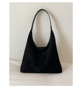 Detailed close-up of a large black tote bag featuring soft matte suede texture material