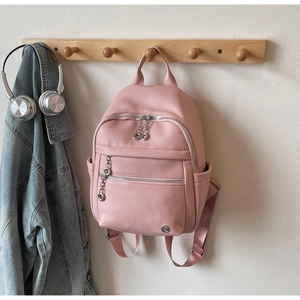 Detail of light pink pebble leather mini backpack with silver chain and metal logo charm