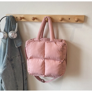 Detailed view of the pink quilted puffer tote bag hanging on a light wooden wall hook