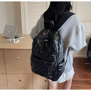 Detail of black glossy quilted backpack with embossed bears and padded straps