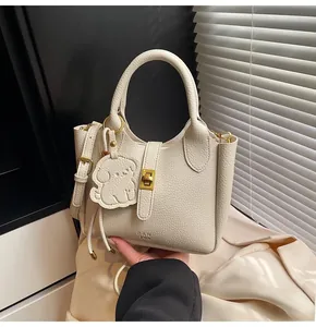 Detailed view of cream lychee texture leather handbag with gold hardware and dog charm