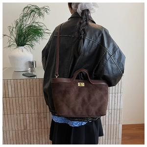 Détail du sac cabas en daim marron avec motif à losanges et fermoir rotatif doré élégant