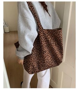 Detailed view of large leopard print canvas tote bag worn on shoulder by a model