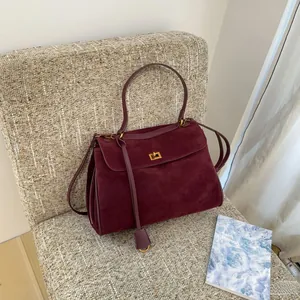 Detailed texture of burgundy suede leather handbag with golden metal twist lock closure