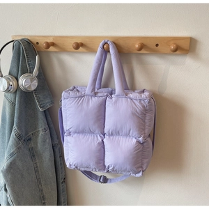 Detailed view of lavender quilted puffer tote bag hanging on wooden hook with casual denim