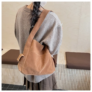 Détail d'un sac cabas marron en daim avec poche latérale à rabat et large bandoulière