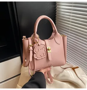 Detail of pink lychee leather handbag with golden twist lock and dog-shaped charm