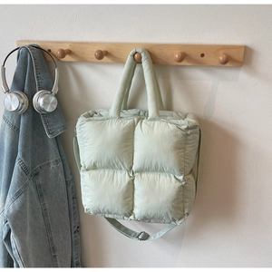 Detail view of light green quilted puff tote bag with adjustable shoulder strap on hook