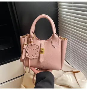 Close-up of pink litchi grain leather bucket bag featuring a cute puppy charm detail