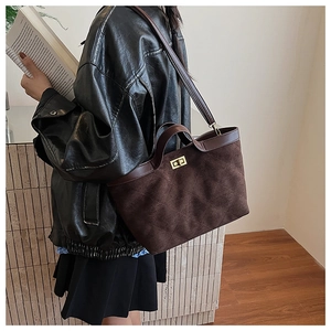 Détail d'un sac cabas matelassé marron foncé avec texture mate et fermoir en métal