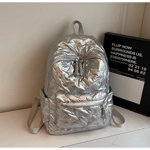 Macro view of silver quilted backpack featuring embossed bow patterns and metal texture