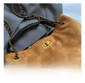 Detailed view of the gold metal twist lock on a brown quilted suede shoulder bag