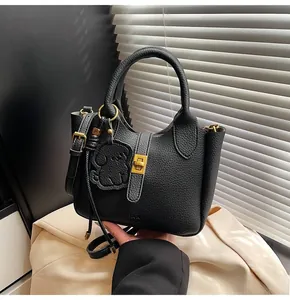 Detail of black lychee leather handbag with gold twist lock and dog-shaped charm