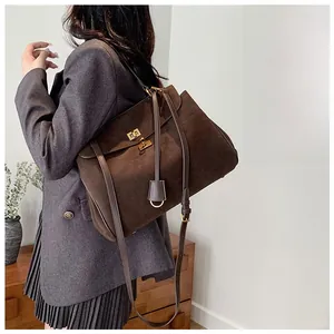 Detail of vintage dark brown suede tote bag featuring a golden twist lock and shoulder straps