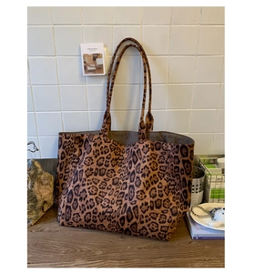Detail of leopard print canvas tote bag with long shoulder straps on a rustic table