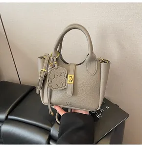 Close-up of litchi texture leather bucket bag with dog charm and metal twist lock