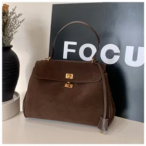 Detail of dark brown suede handbag with golden metal twist lock and matte texture finish
