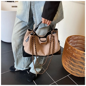 Detail of khaki suede bucket bag with quilted patterns and metal chain strap