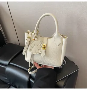 Detail of off-white lychee texture bucket bag with gold lock and dog pendant charm