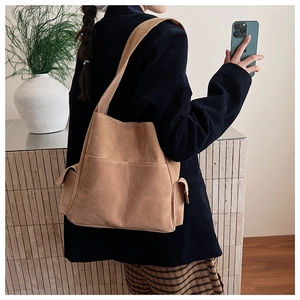Vue latérale d'un grand sac fourre-tout en daim marron porté par un mannequin