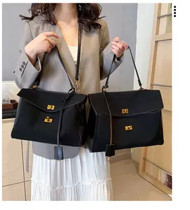 Vue détaillée d'un sac cabas noir en cuir avec fermoir doré rotatif et doubles bandoulières
