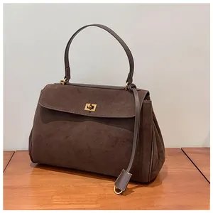 Detail of vintage dark brown frosted leather handbag with elegant gold metal twist lock