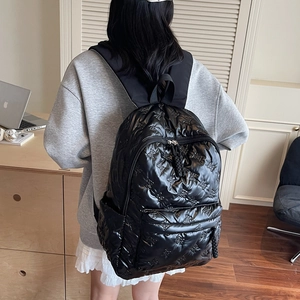 Black quilted backpack with bow patterns in nylon fabric shown on model in a modern office