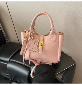 Detailed view of pink lychee leather handbag with gold twist lock and puppy charm