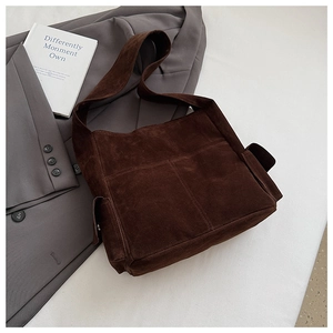 Détail du cabas en daim marron foncé avec poches avant sur une veste grise