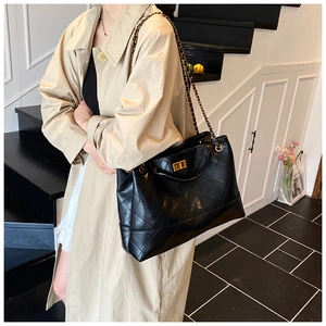 Close-up of elegant black quilted tote bag with golden twist lock and chain strap