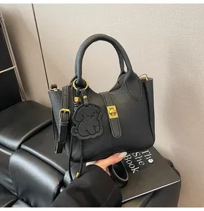 Detail of black lychee grain bucket bag with gold twist lock and leather puppy charm