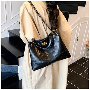 Detail of black quilted leather shoulder bag with gold chain strap and metal swivel lock