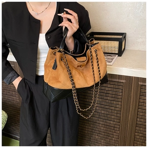 Detailed close-up of brown suede and black leather bucket bag with quilted chain straps