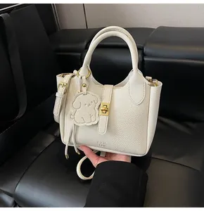 Close-up of white lychee leather bucket bag with gold lock and cute dog pendant