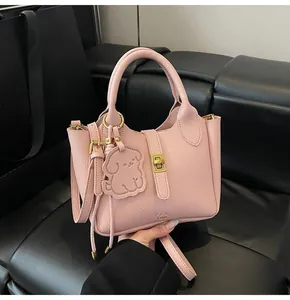 Detailed macro view of pink lychee grain leather handbag with gold lock and puppy charm