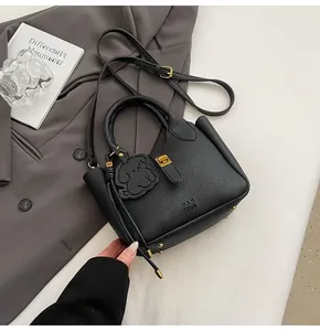 Close-up of black lychee grain leather bucket bag with dog charm and gold hardware